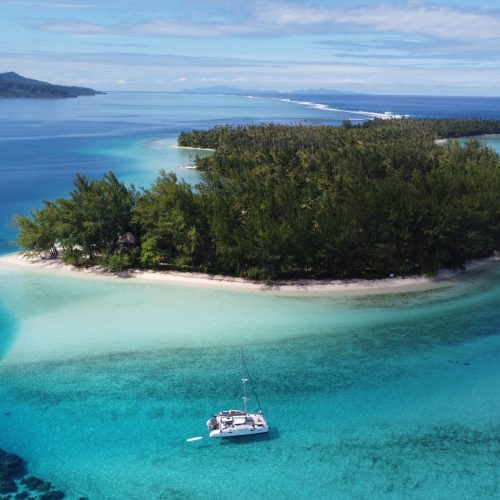 Aerial view of a catamaran cruising through clear blue waters