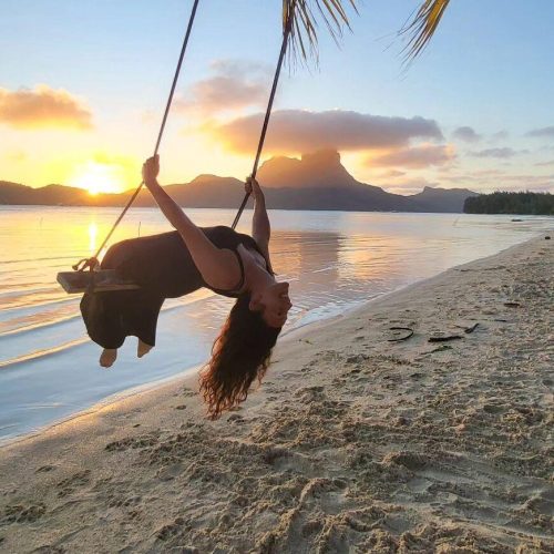 Traveler swinging on a beach swing in French Polynesia at sunset